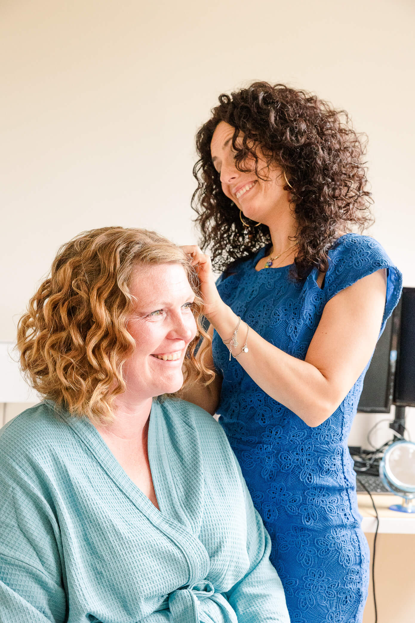 A hairdresser finishes touches on a bride's curly red hair for her special wedding day.
