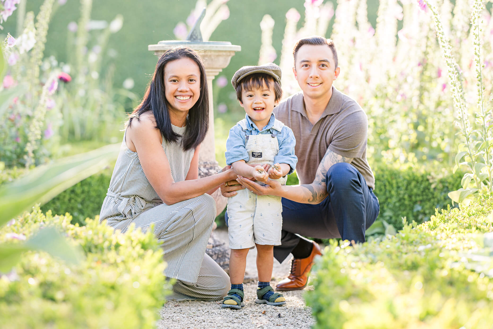 A mom and dad play with their son as he picks up rocks and looks for fun things to do in Oxford with kids.