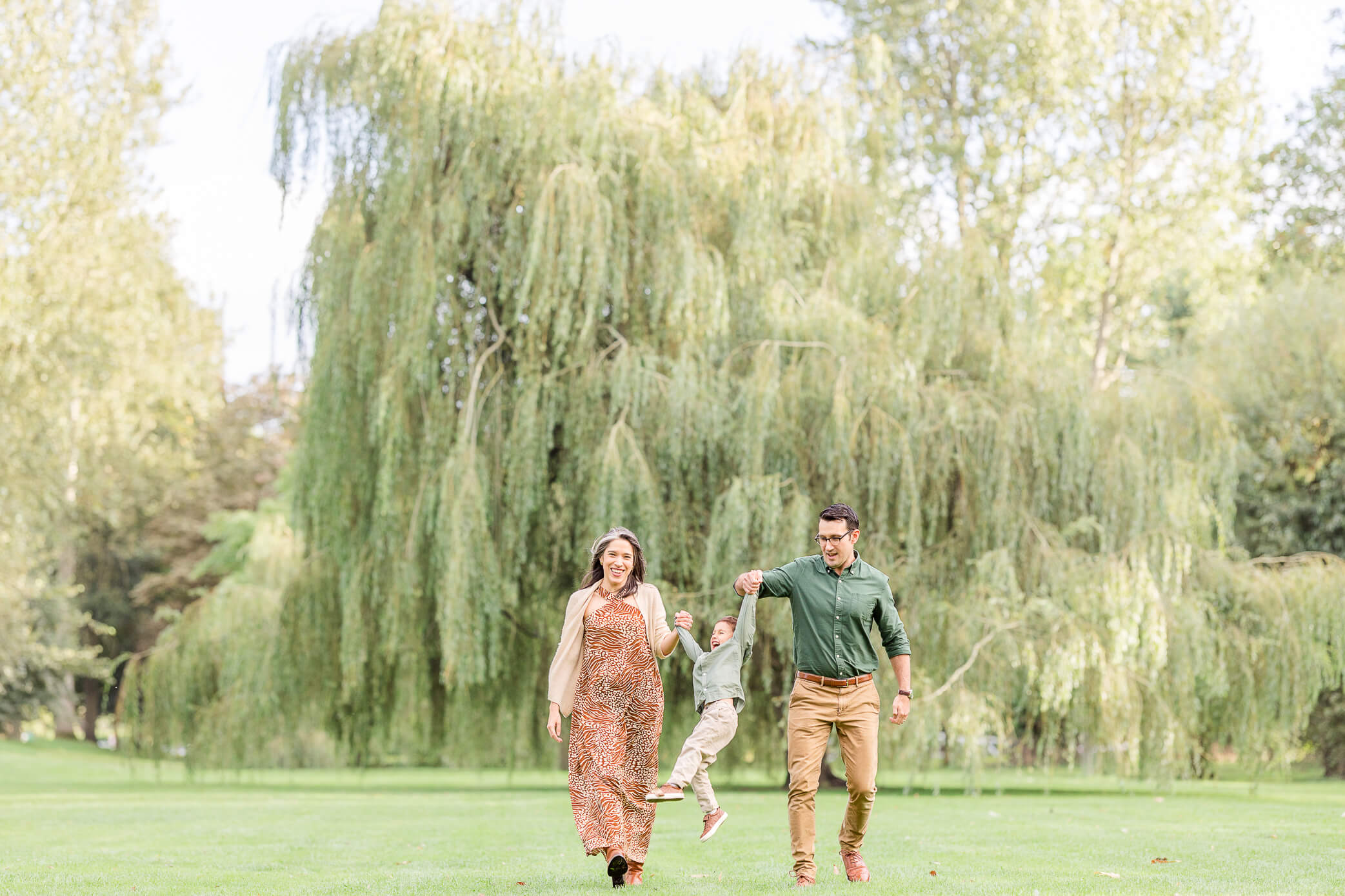 Parents look for fun things to do in Oxford with kids while holding their son's hands and swinging him back and forth in a park.