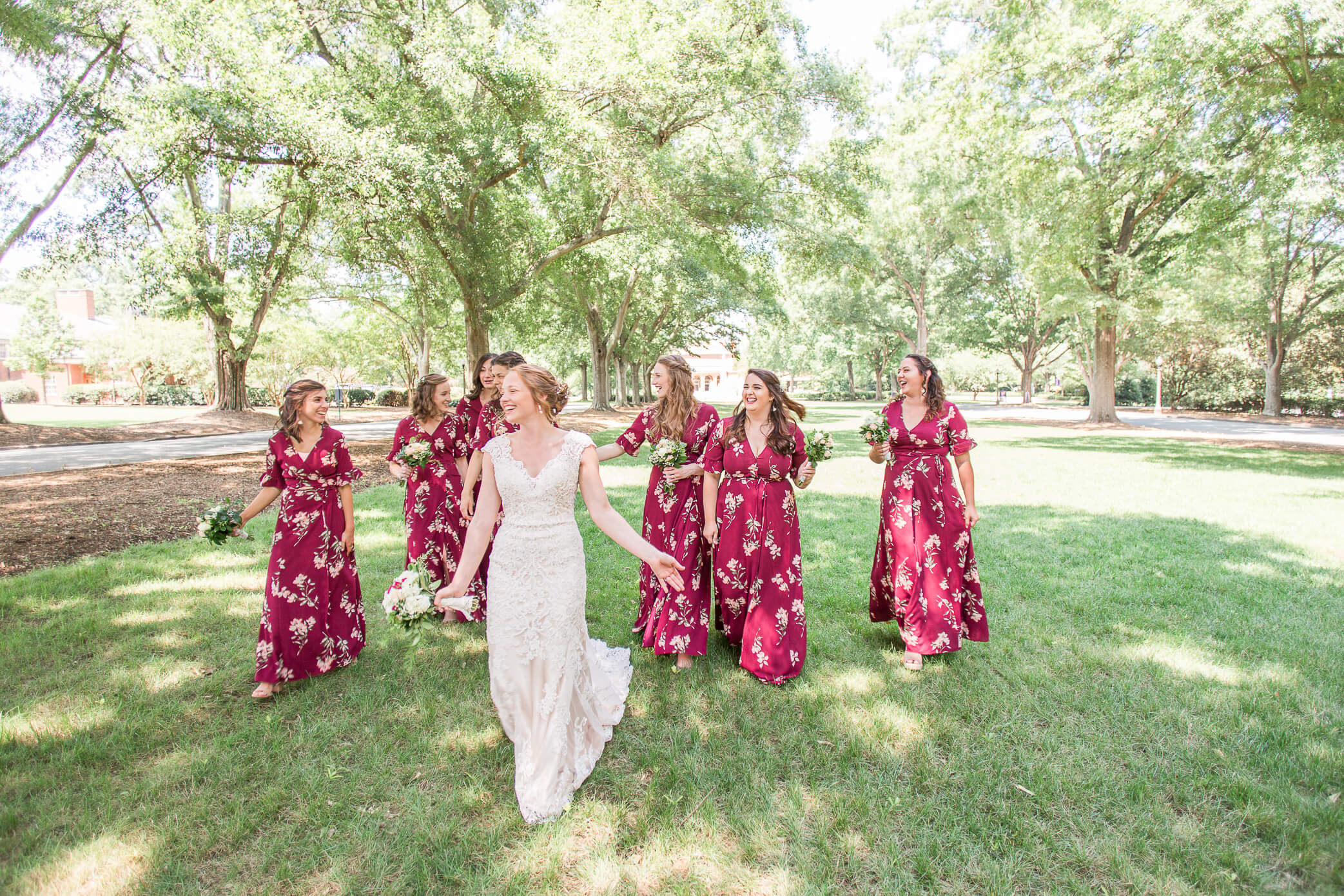 A bride and her bridesmaids walking down a grassy path surrounded by trees and gorgeous weather