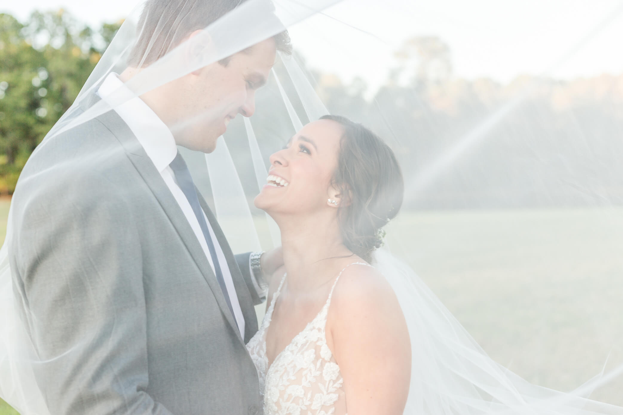 A bride and groom share an intimate moment together as they snuggle close beneath the bride's veil during their Woodstock wedding