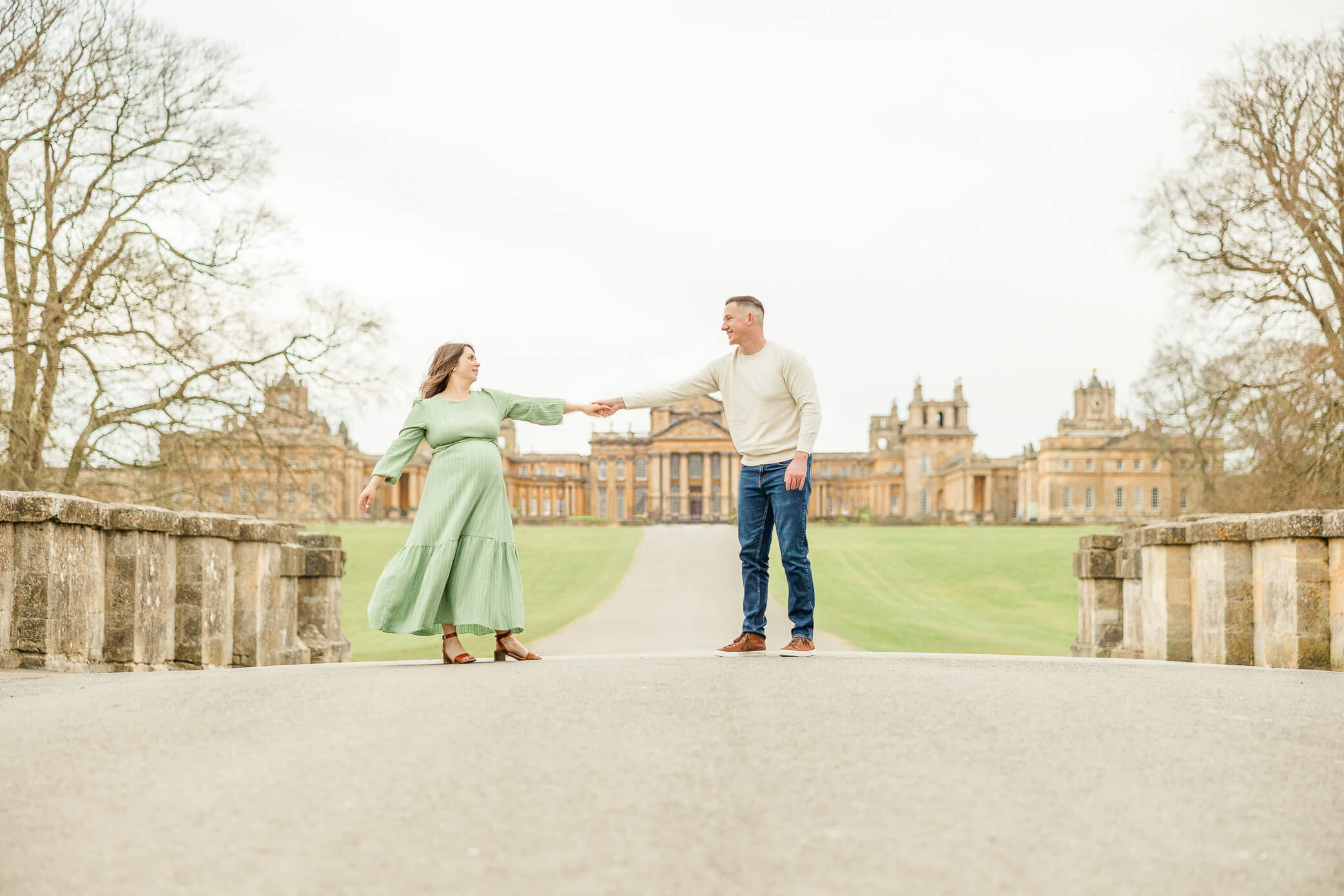A newly married couple dances together on a bridge in front of Blenheim Palace.