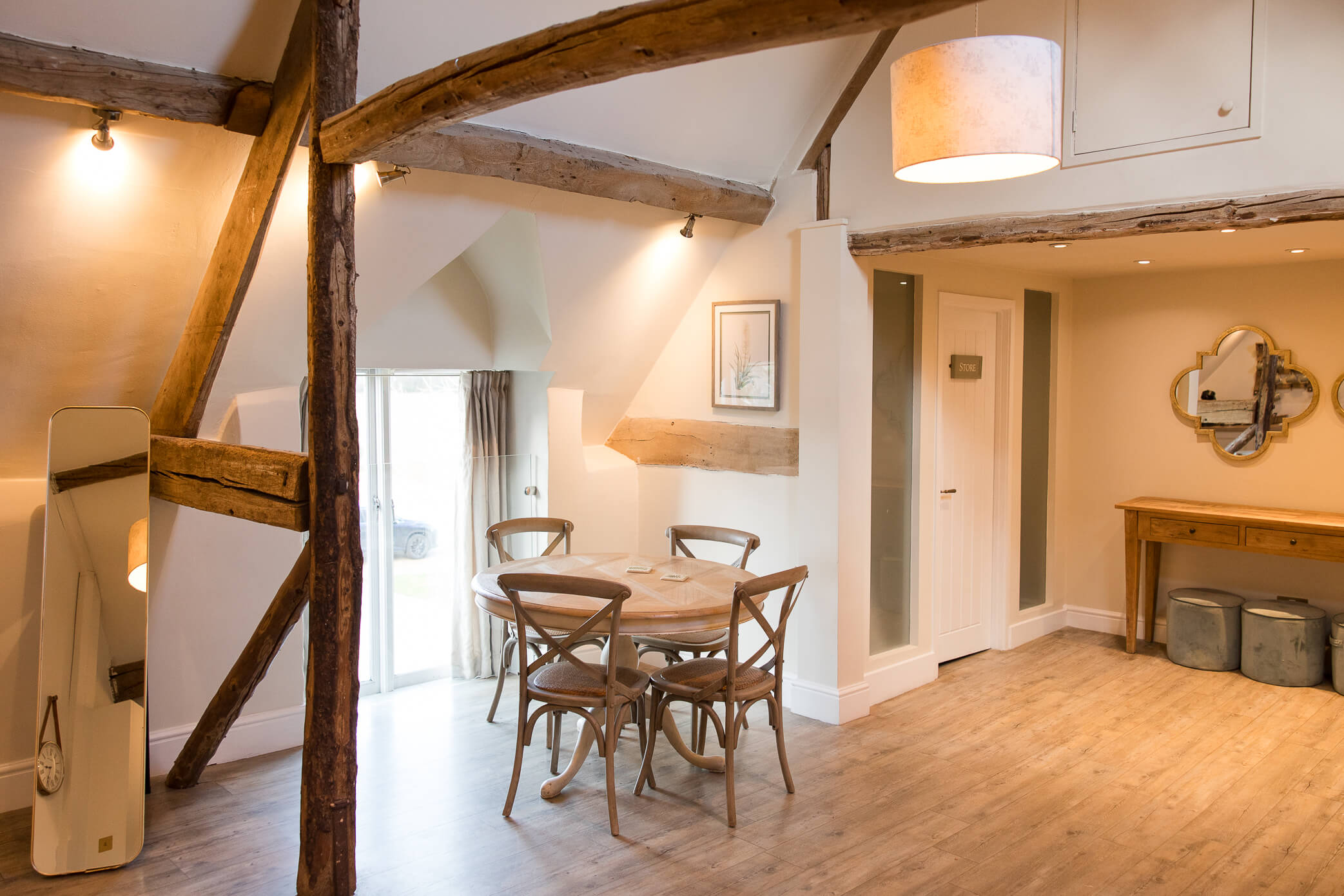 Table and chairs with a window in a converted barn.