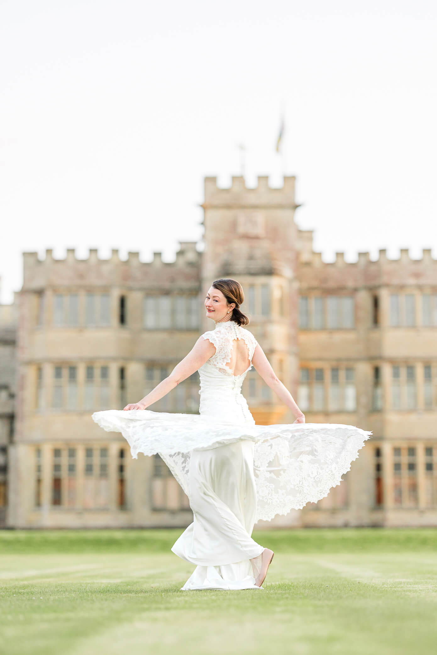 A bride twirls on the green behind the Rousham House wedding 