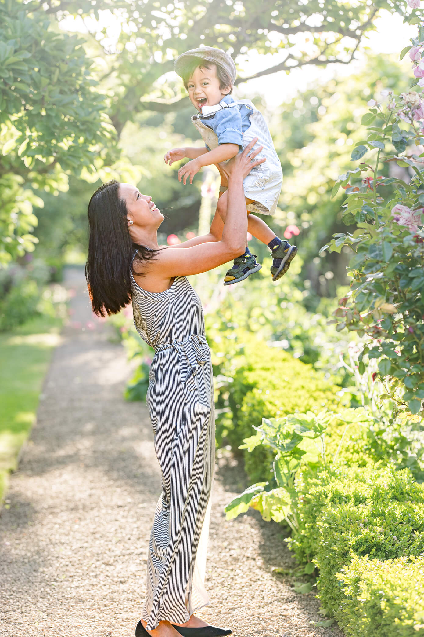 A mother raises up her young son as if she is about to toss him up as he laughs and enjoys playing