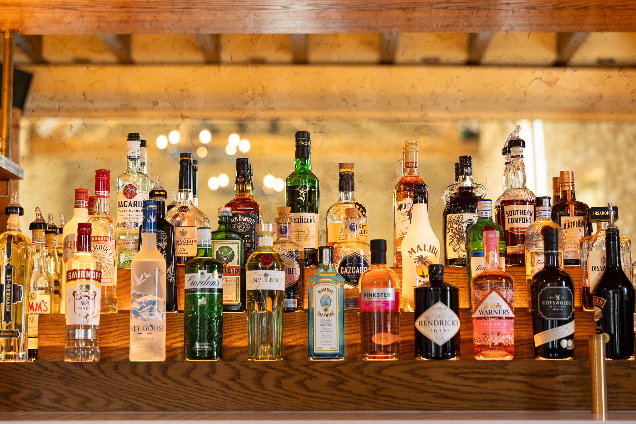 Fully stocked bar of liquor on tiered shelving