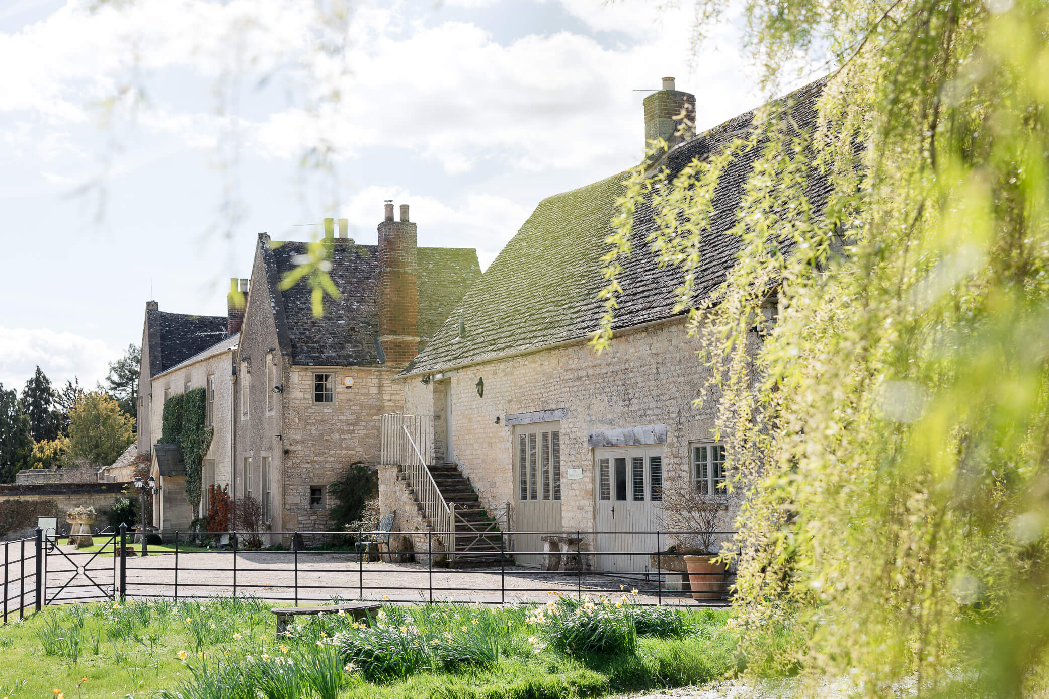 A side view of Caswell House with a weeping willow and small pond in the foreground