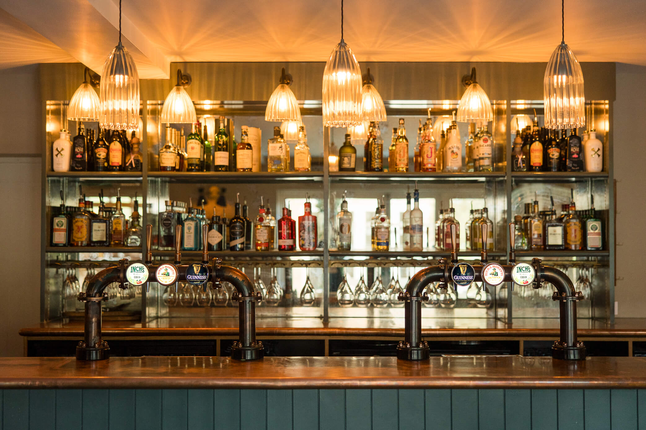 A copper-topped, fully stocked bar with ambient lighting