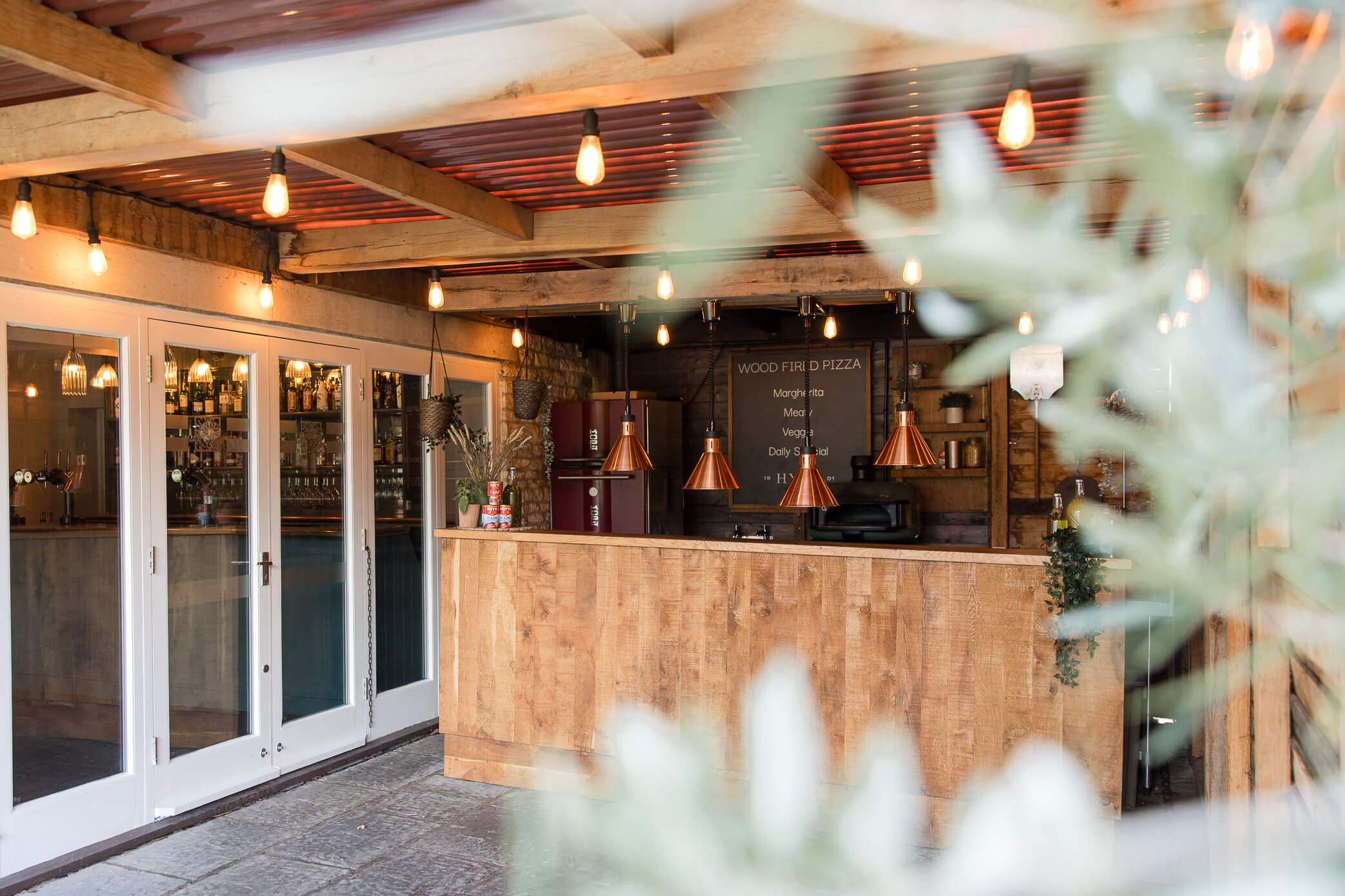 Wood-fire pizza oven on the patio with hanging copper lighting