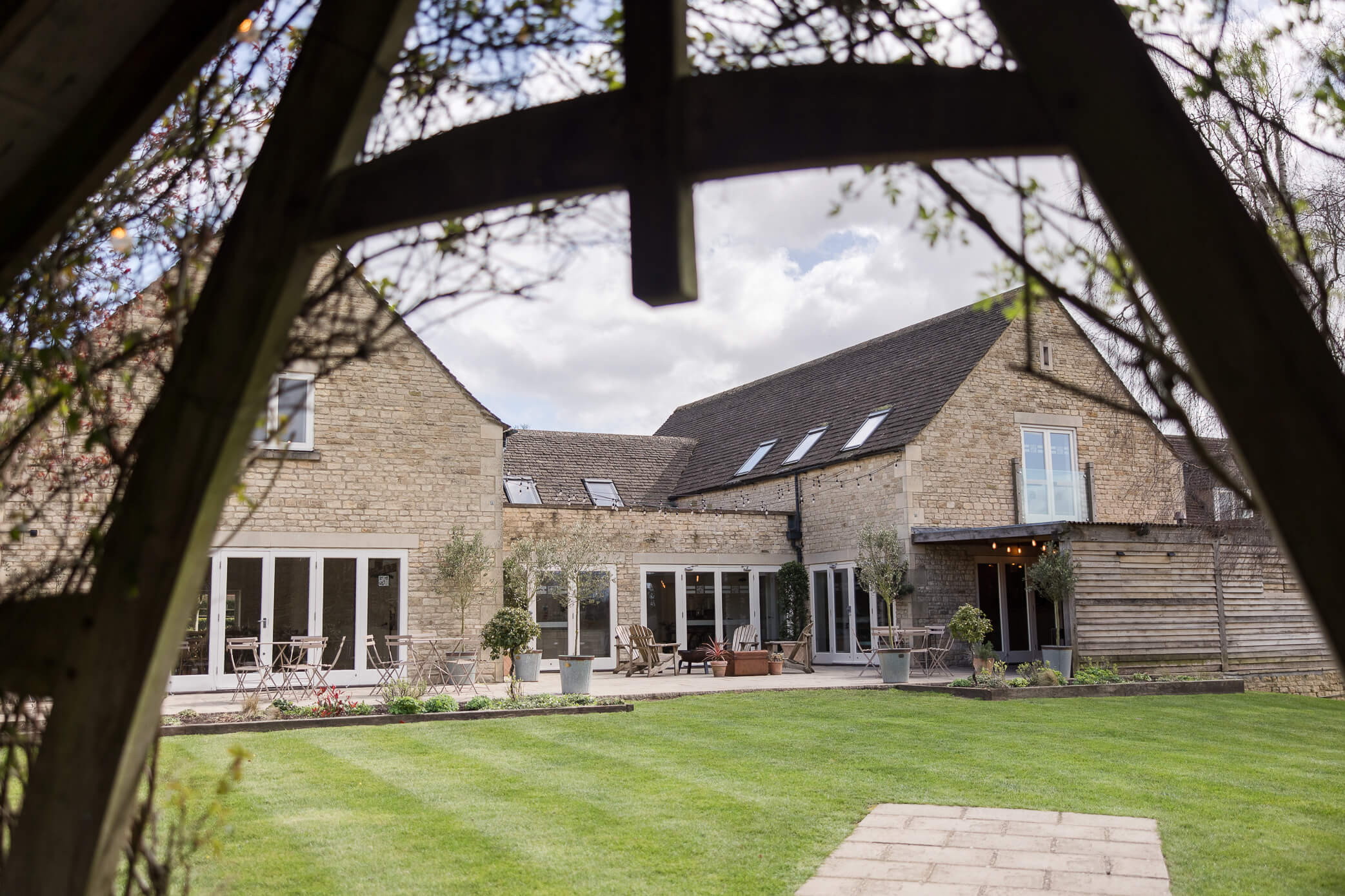 The back garden area of Hyde House from beneath the Arbour. There is a firepit and chairs in the distance