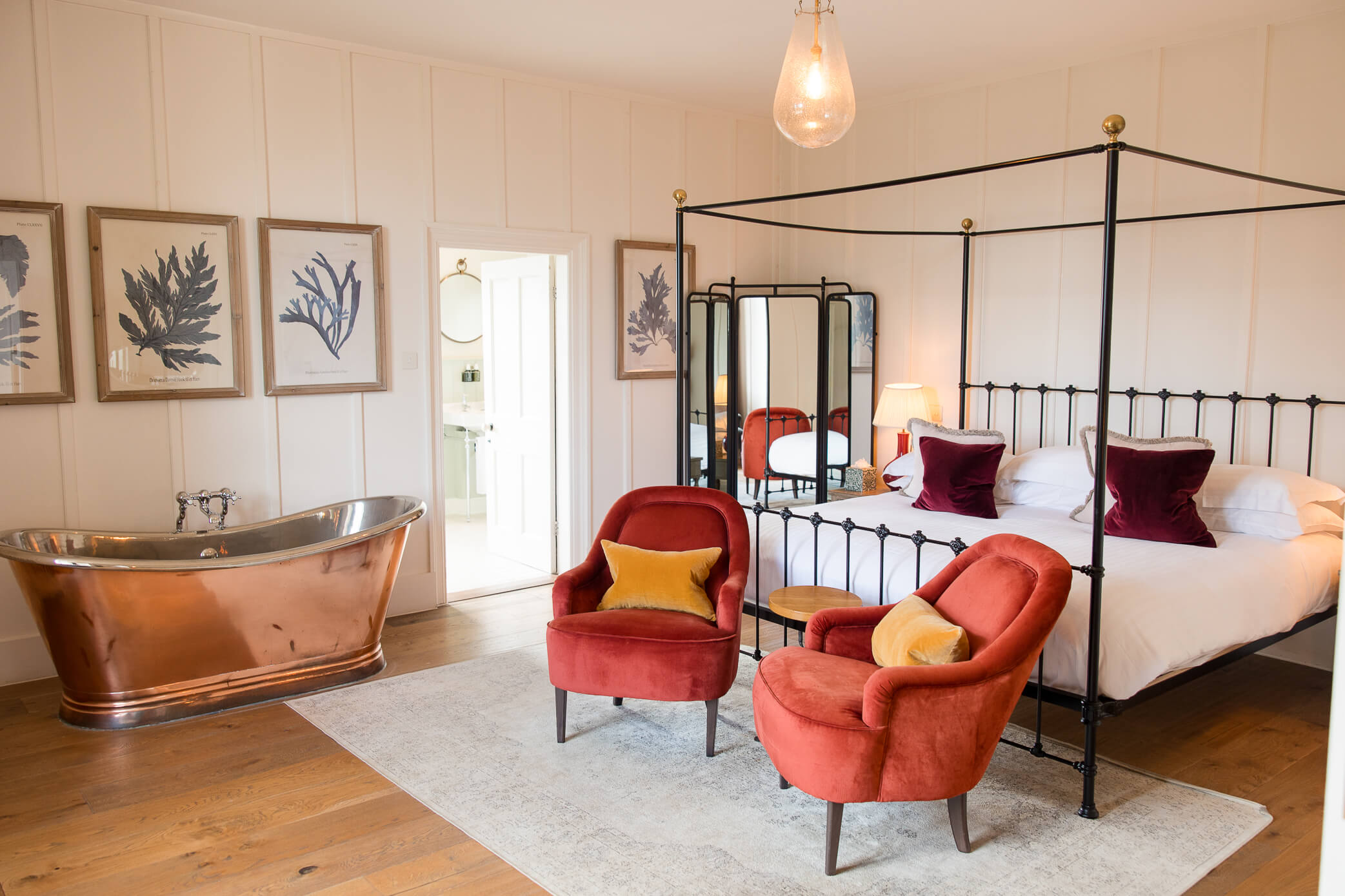 The Honeymoon Suite which hosts the newlyweds after a Hyde House wedding. Features a large bed, two velvet chairs, and a copper bathtub