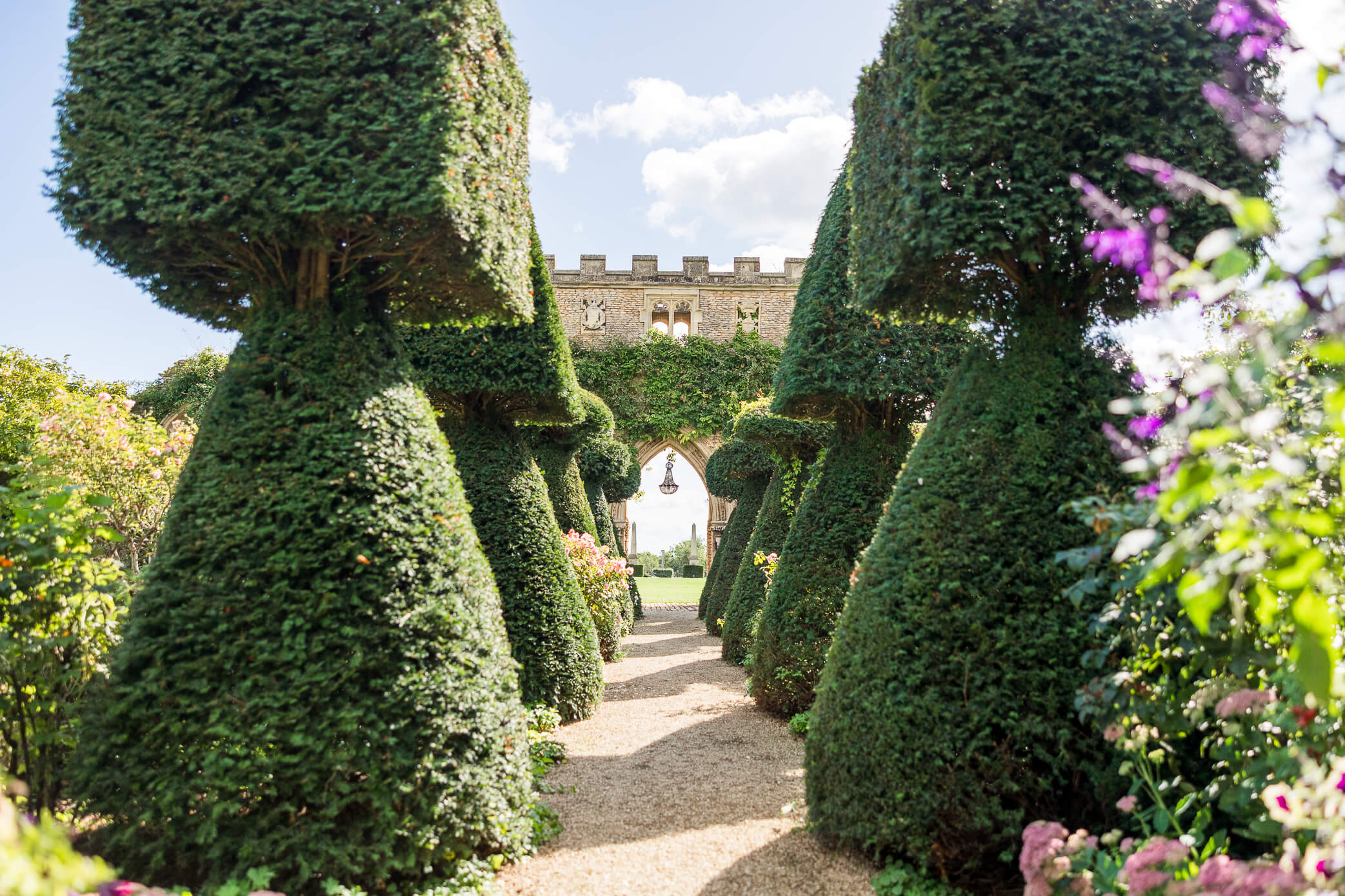Castle Arch with a crystal chandelier hanging from the ruins, surrounded by topiary bushes