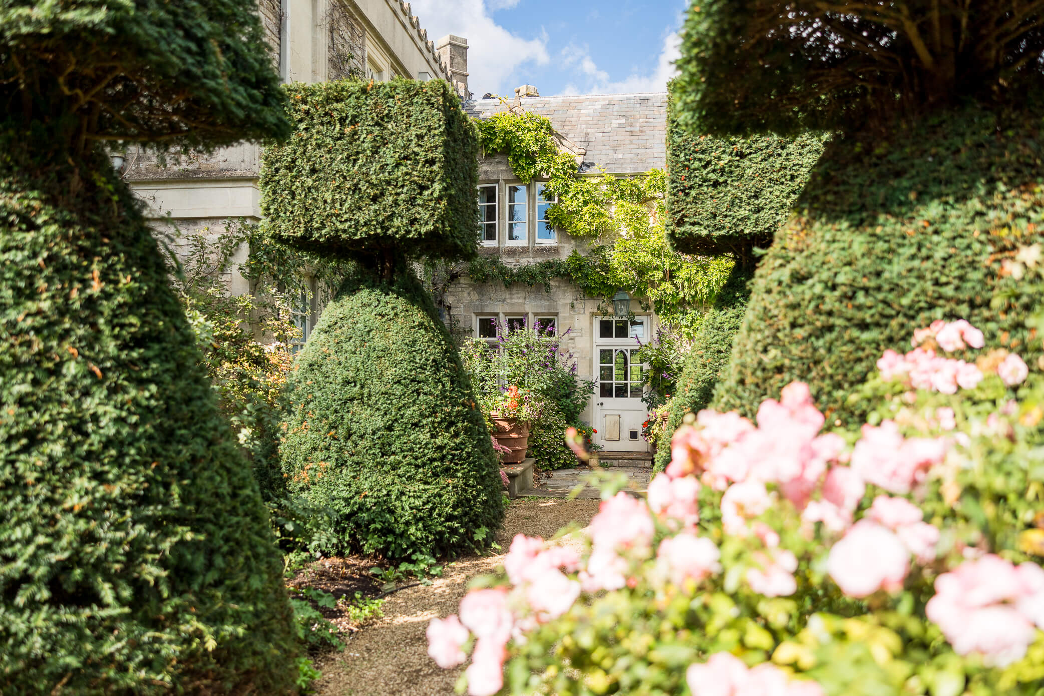 the Cloisters as shot from the outside surrounded by topiary and roses